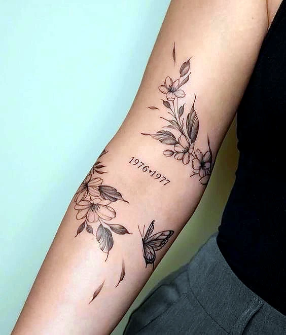 Floral and butterfly tattoo with date by Rav Singh at Inkology